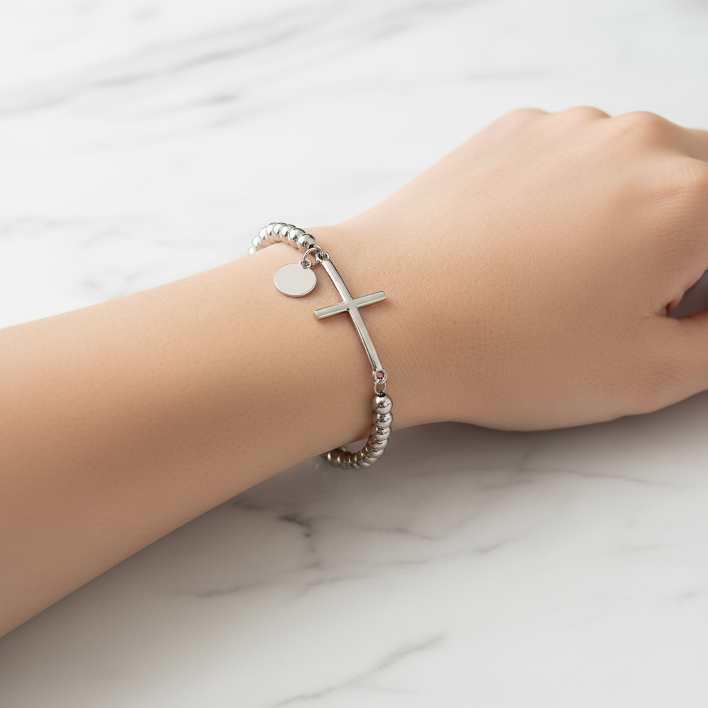 Steel silver beaded cross bracelet on wrist - marble background